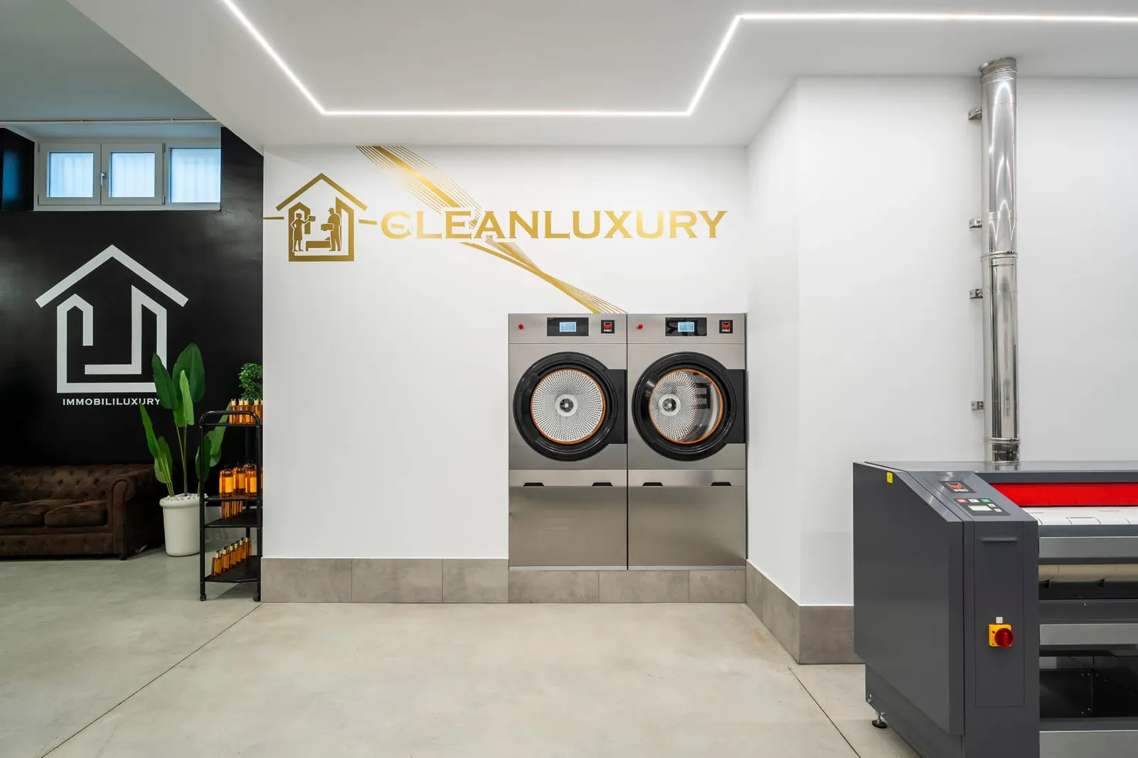 Area di lavaggio di Clean Luxury Group con due macchine professionali e insegna a parete