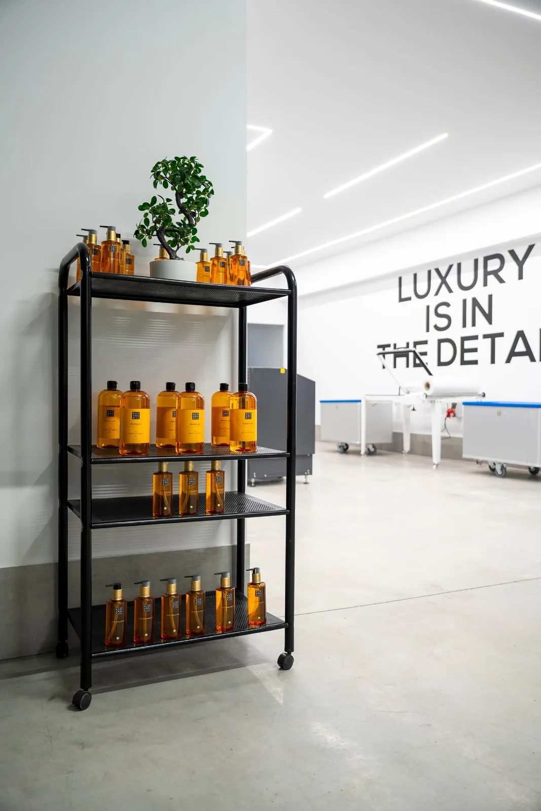 Carrello con prodotti da bagno per le camere accanto alla scritta a parete Luxury is in the detail